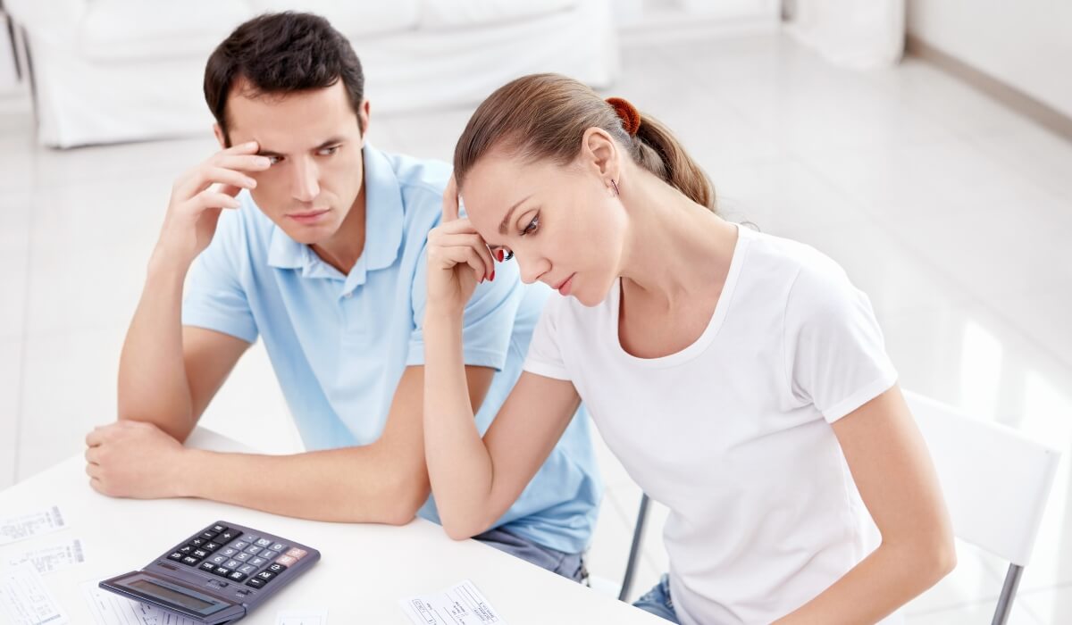 A stressed couple reviews bills during infertility related financial strain.