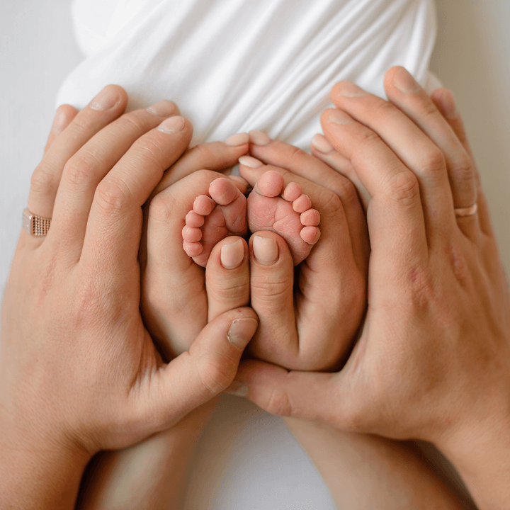 Newborn baby feet cradled gently in adult hands